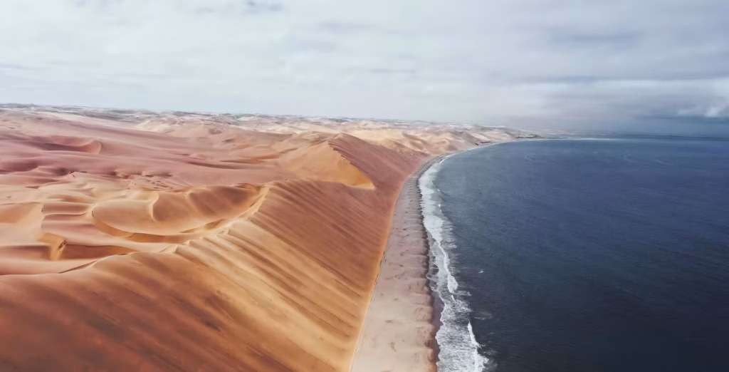 Sandwich Harbour in Namibië, met hoge zandduinen, strand en de oceaan.