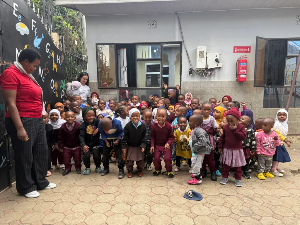 Een groep kinderen in Daisy Daycare Tanzania, met een leraar aan de linkerkant.